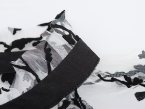 Macro shot of breathable white mesh fabric featuring elegant black flocked vintage patterns