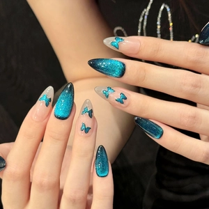Macro shot of long stiletto press-on nails with dark blue cat-eye effect and butterfly decals
