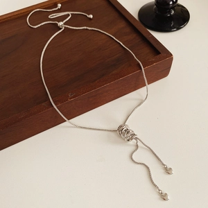 Detail of silver zircon circle pendant necklace with heart charms on wooden tray