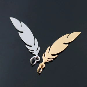 Macro detail of gold and silver feather pendants with closed jump rings on black background