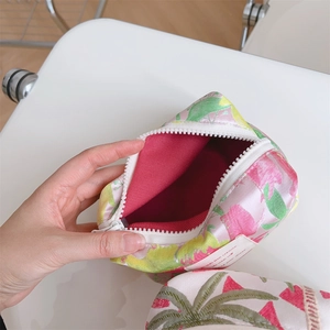 Detail showing the inner lining and floral jacquard pattern of the pink boat-shaped pouch