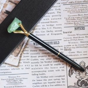 Stylo à bille en métal noir avec griffe dorée sertie d'une pierre de cristal vert