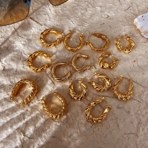 Chunky gold croissant hoop earrings set in various sizes on a neutral textured background