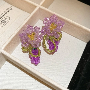 Detail of purple handmade beaded flower earrings featuring intricate crystal tassels