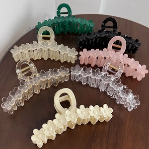 Set of 13cm flower shaped acrylic hair claws in multiple colors on a wooden surface