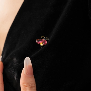 Macro shot of vintage insect brooch with pink and black stones on black velvet