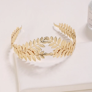 Detail of golden metal leaf headband featuring retro baroque crown style in soft lighting