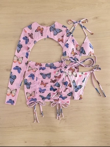 Detail of pink butterfly print mesh cover-up and four-piece bikini set on wood
