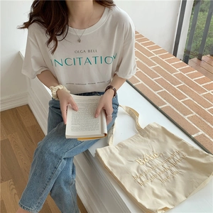 Nahaufnahme des weißen Baumwoll-T-Shirts mit grüner INCITATION Stickerei und weichem Stoff