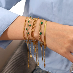 Vergoldetes Edelstahl-Armband-Set mit grünen Zirkoniasteinen am Handgelenk eines Models