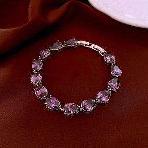 Detailed macro view of pear-cut purple zircon gemstones in a silver-plated twisted bracelet