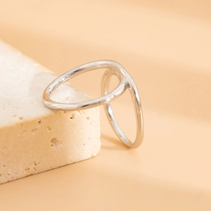 Dettaglio macro dell'anello argento a doppio giro intrecciato su base in travertino