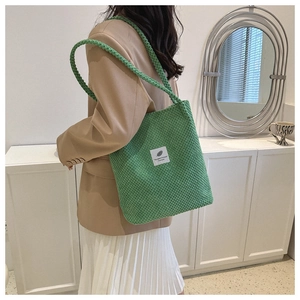 Detail of green corduroy bucket bag with a white 'You need this one' label and strap