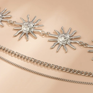 Detailed close-up of multi-layer silver metal waist chain with sun smile pendants