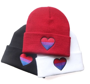 Detailed close-up of bisexual pride flag heart embroidery on knit beanies in three colors