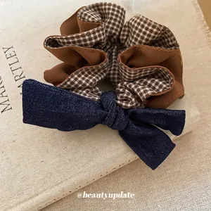 Retro plaid bow scrunchie with denim detail on textured fabric background