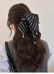 Détail d'un chouchou à nœud rayé noir et blanc avec des breloques en perles fantaisie