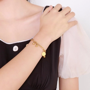 Bracciale a sfere placcato oro boho con ciondolo a moneta indossato da una modella