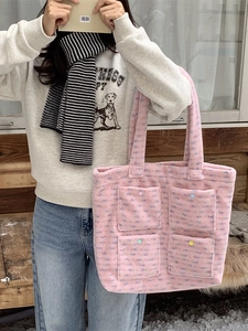 Pink plush tote bag with four colorful button pockets shown in a winter outdoor setting