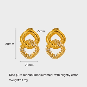 Detailed view of gold earrings with spiral texture and white cubic zirconia accents
