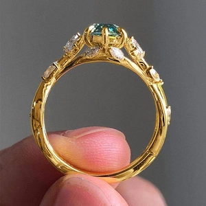 Detail of luxury gold ring with round teal stone and marquise cubic zirconia accents