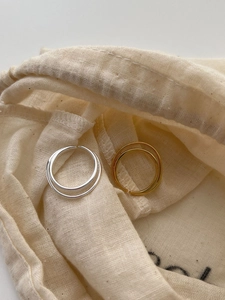 Detail of double-layered sterling silver rings on a minimalist beige linen texture bag