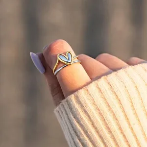 Elegant two-tone heart crossover ring in gold and silver finish worn by a woman
