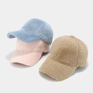 Détail de casquettes de baseball en fausse fourrure bleue, rose et kaki, texture douce