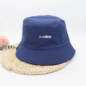 Detail of dark blue cotton bucket hat featuring a white whale embroidery on woven mat