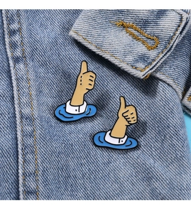 Close-up of two cute enamel thumb pins on a denim jacket collar for waist adjustment