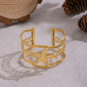 Detail of 18K gold plated cuff bracelet with starfish element and braided hollow pattern