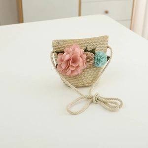 Detail of hand-woven straw crossbody bag with colorful fabric floral decorations