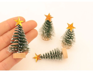 Close-up of mini green frosted Christmas tree with gold star and round wooden base