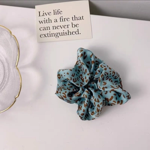 Detail of silk hair scrunchie with blue and brown leopard pattern on white background