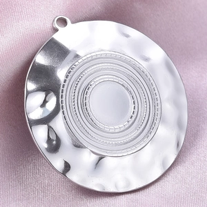 Close-up of silver hammered 304 stainless steel round pendant on pink silk background