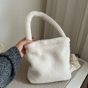 Close-up of white plush faux fur tote bag with thick handle in a home setting