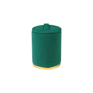 Emerald green velvet jewelry box with golden metal base and ring handle in a minimalist style