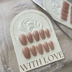 Reusable nude pink coffin-shaped press-on nails set on an elegant white embossed card