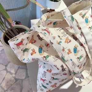 Detail of canvas tote bag featuring red polka dots and colorful cartoon puppy prints