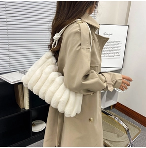 Detail of white plush striped shoulder bag with stylish knotted strap worn by a model