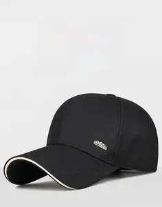 Detail of black baseball cap with contrast beige brim edge and metal sports style plaque