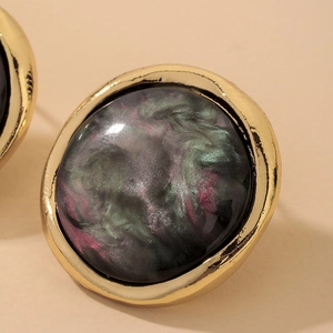 Macro shot of vintage resin stud earrings with golden edges and nebula pattern