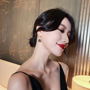 Elegant circular black drop earrings with gold metallic edges worn by a model
