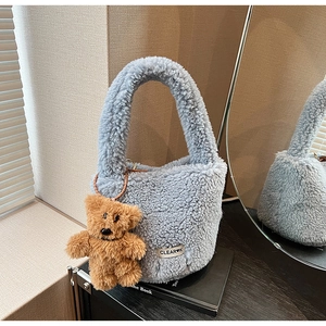 Detail of light blue faux shearling bucket bag with cute bear charm and logo tag
