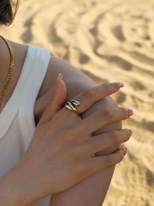 Close-up of dual-tone gold and silver fluid ring worn by model in desert setting