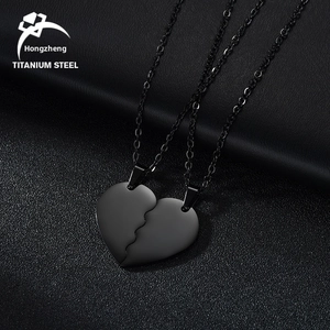 Detail of matte black titanium steel heart puzzle necklaces for couples on dark background