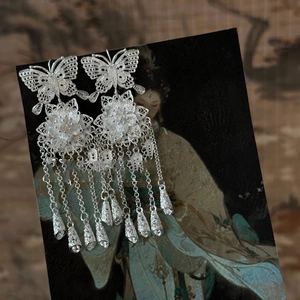 Detail view of hollow butterfly and floral tassel earrings in silver filigree style