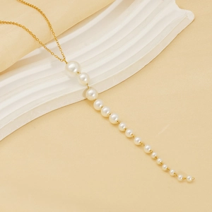 Détail de collier doré élégant avec pampille de perles blanches en cascade
