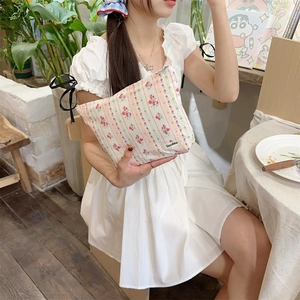 Floral cotton makeup bag held by a model in a white dress for a fresh lifestyle look