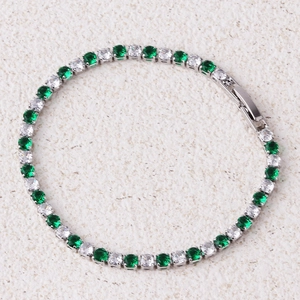 Detail van een zilveren tennisarmband met afwisselend groene en witte zirkonia-stenen